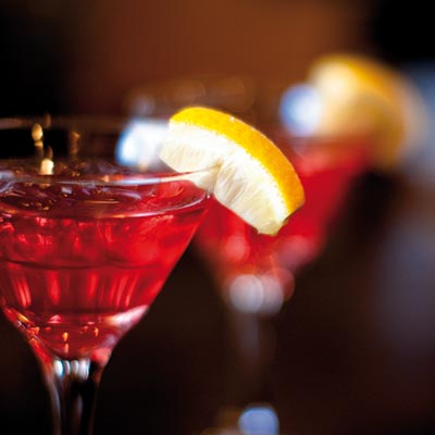 Two cocktail glasses on a bar